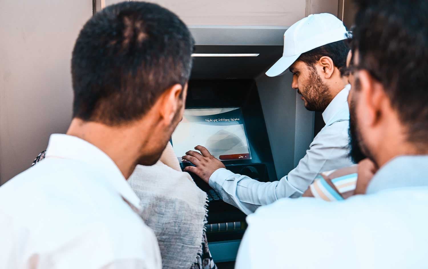 A MyAccount staff member instructs public servants how to withdraw their salary from an ATM. File photo: Rudaw