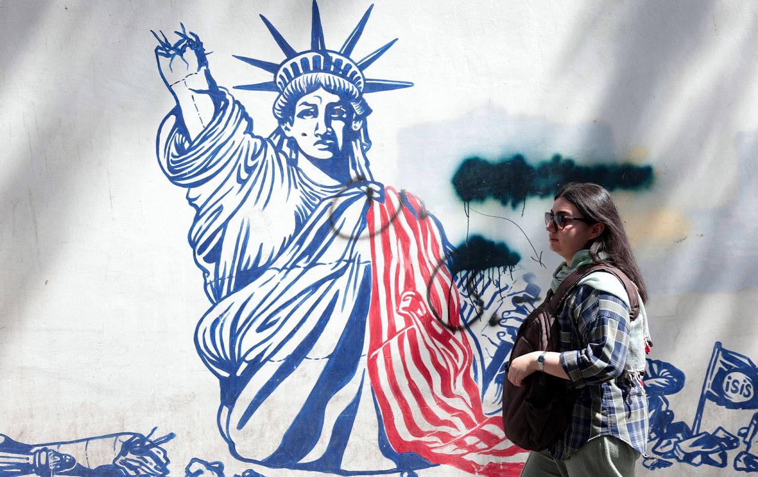 A woman walks next to an anti-US mural near the former US embassy in Tehran May 11, 2025. Photo: Atta Kenare/AFP