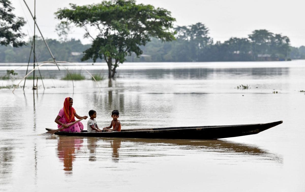 ژنێک و دوو منداڵ لەنێو بەلەمێکی بچووکدان لە ناوچەیەکی زیانبەرکەوتوو بە لافاو لە هیندستان. وێنە: AFP