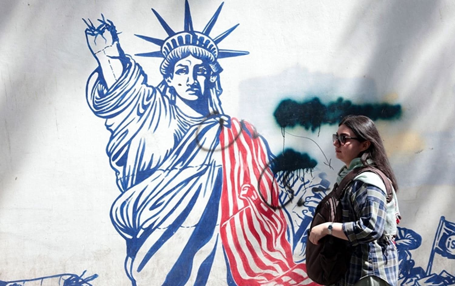 A woman walks next to an anti-US mural near the former US embassy in Tehran May 11, 2025. Photo: Atta Kenare/AFP