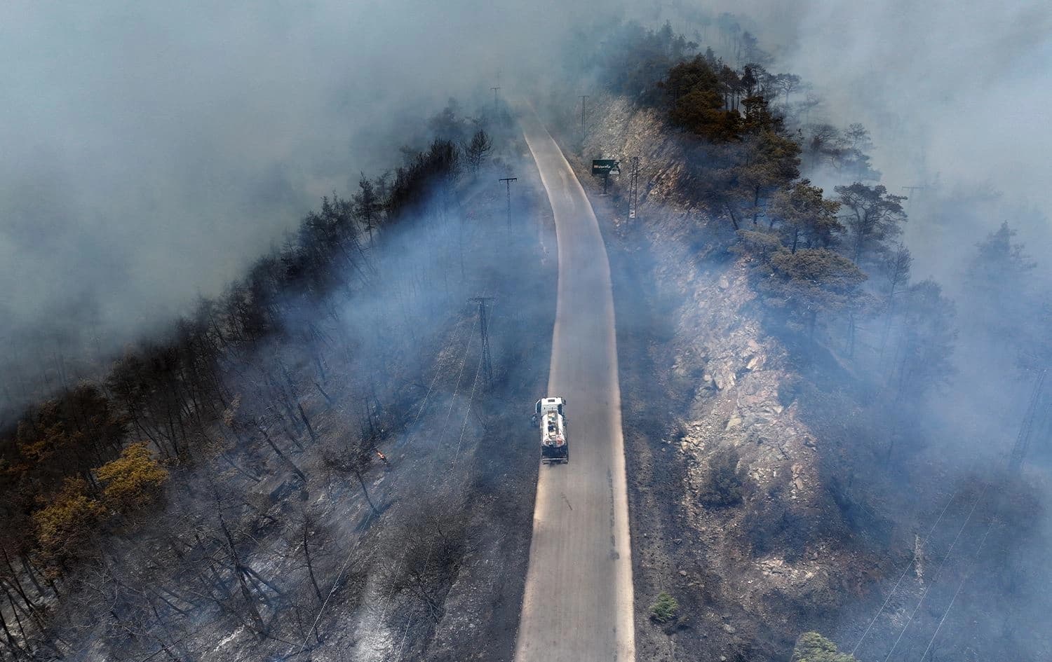 An aerial view shows a fire truck driving down a road as firefighters battle forest fires in the coastal Syrian province of Latakia on July 5, 2025. Photo: Omar Haj Kadour/AFP