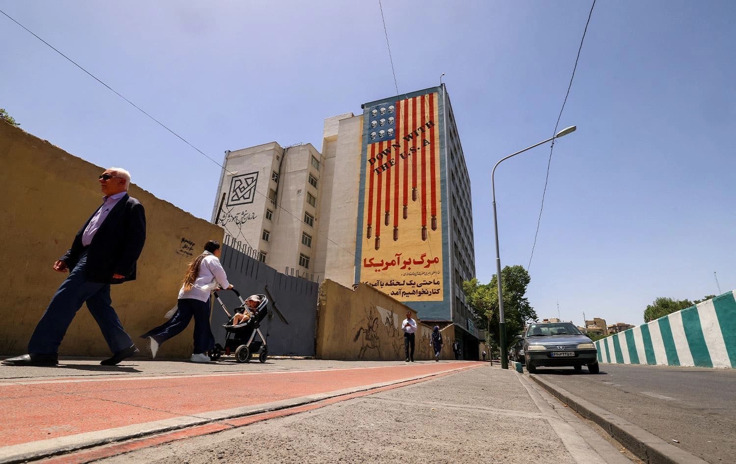 People walk near anti-US mural with the slogan "Down with the USA" and skulls replacing the stars on the flag, in Tehran, on May 20, 2025. Photo: Atta Kenare/AFP