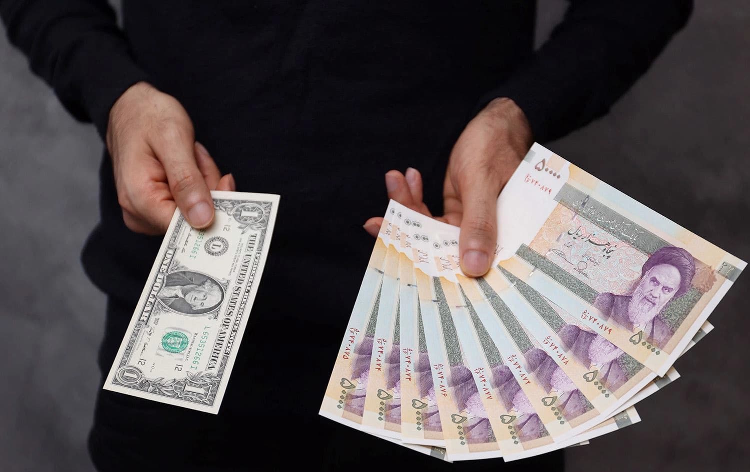 کەسێک دۆلارێکی ئەمریکی و بڕێک تمەنی ئێرانی بەدەستەوەیە وەکو ئاماژەیەک بۆ هەواڵەکە وێنەکە دانراوە