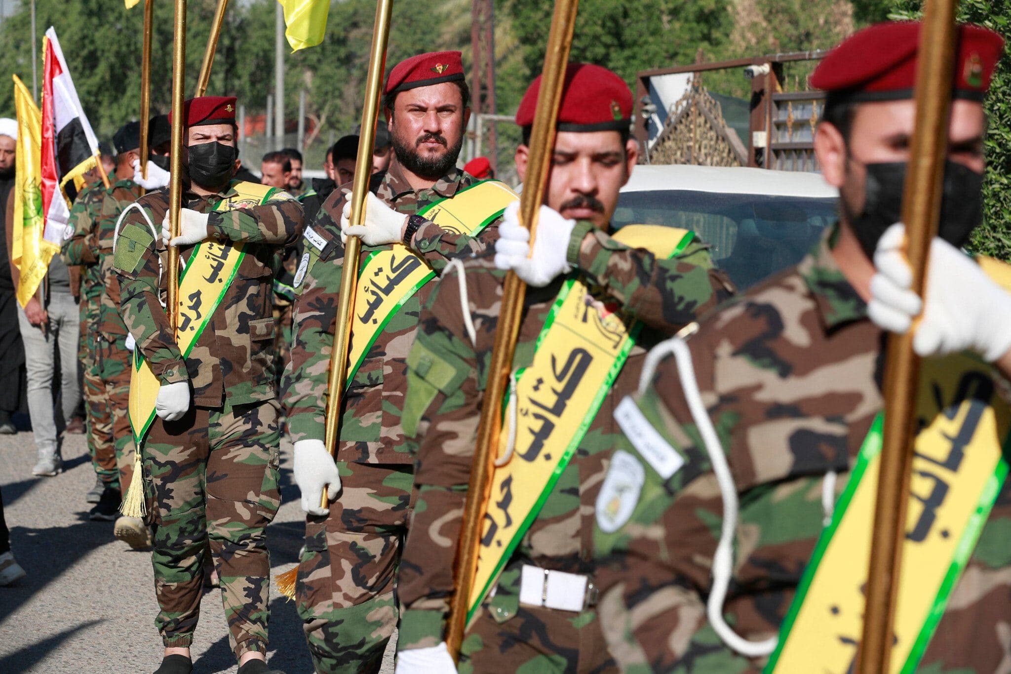 Fighters lift flags of Iraq and Harakat Hezbollah al-Nujaba, during a funeral in Baghdad in December 2023. AFP file photo