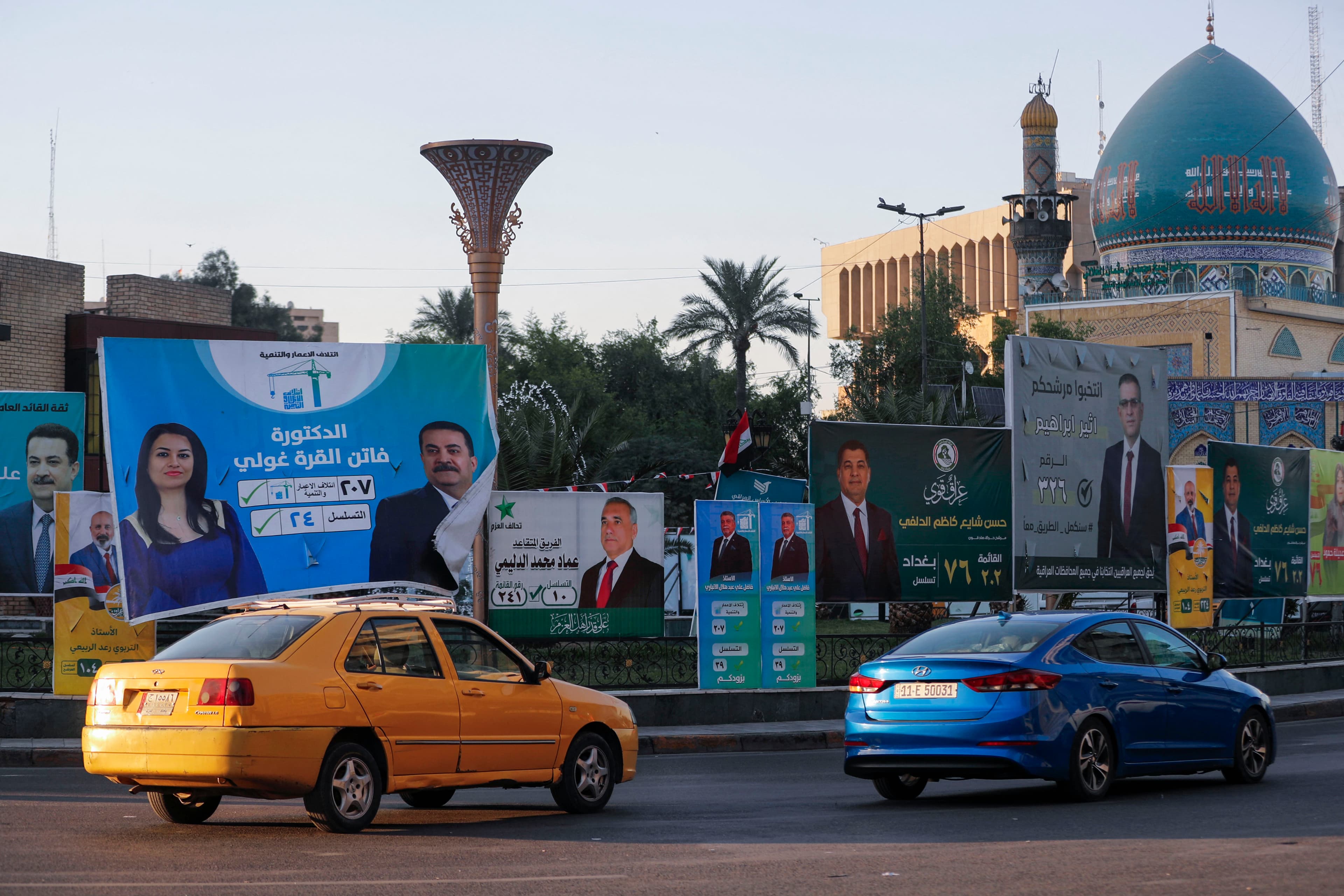 People drive their vehicles past electoral billboards on a street in Baghdad on October 14, 2025. Photo: AFP