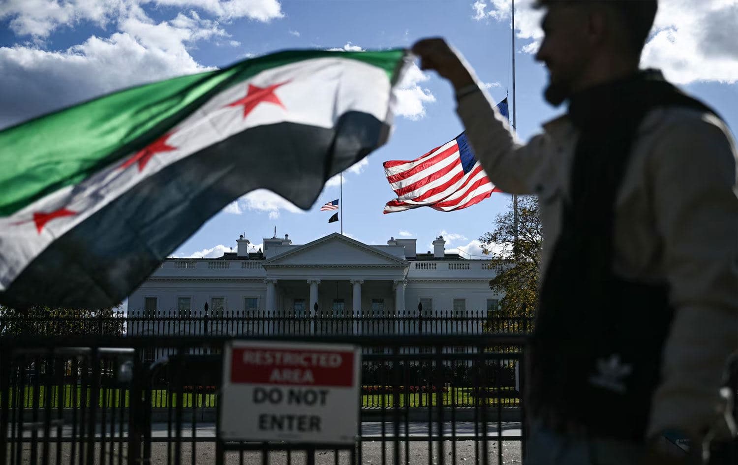 A man holds a Syrian flag across the street from the White House after Syrian president Ahmed al-Sharaa met with US president Donald Trump. Photo: AFP