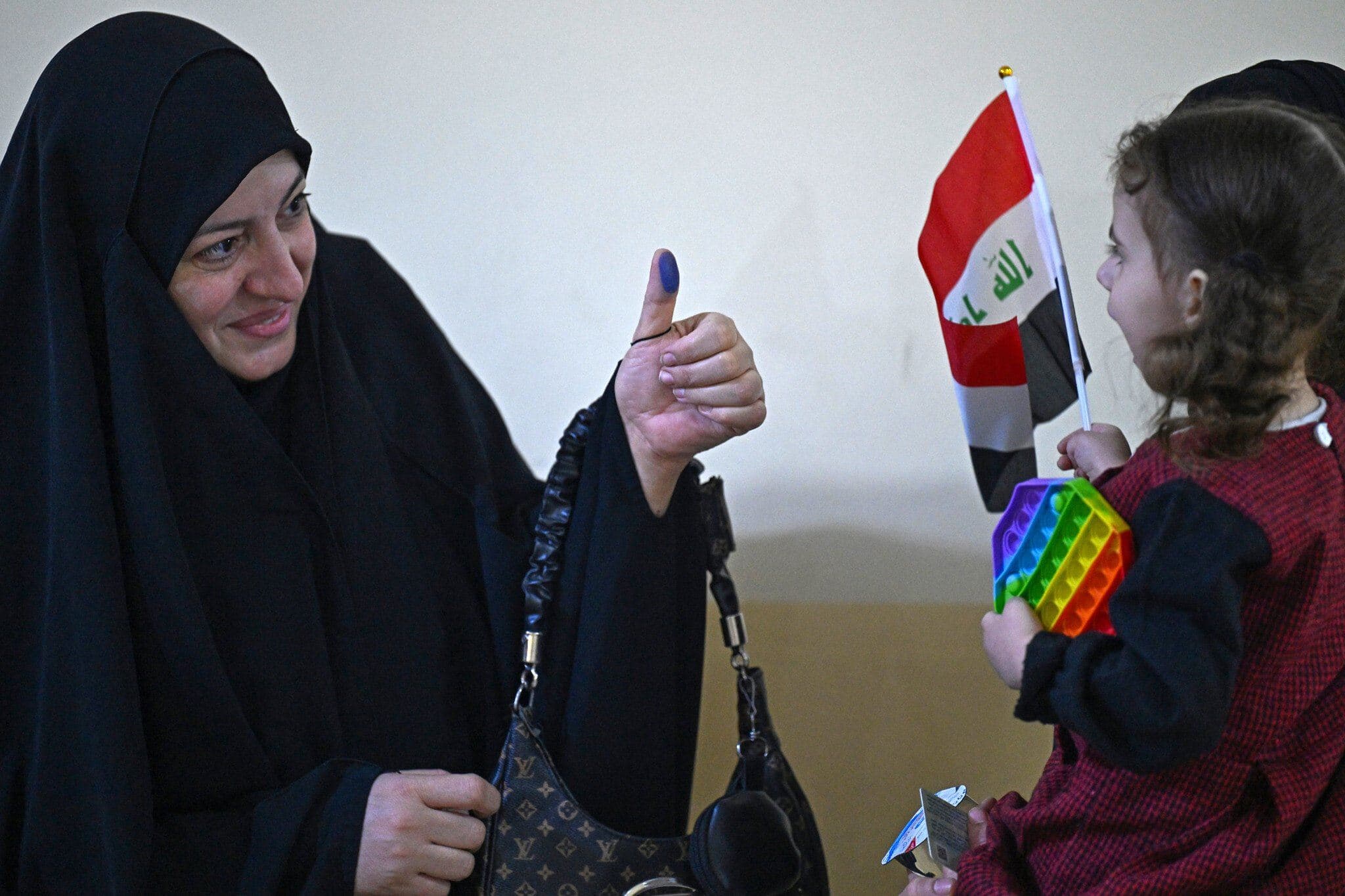 An Iraqi voter shows her ink-marked thumb to her family members after casting her ballot at a polling station in the southern city of Basra on November 11, 2025 during Iraq's parliamentary elections. Photo: AFP