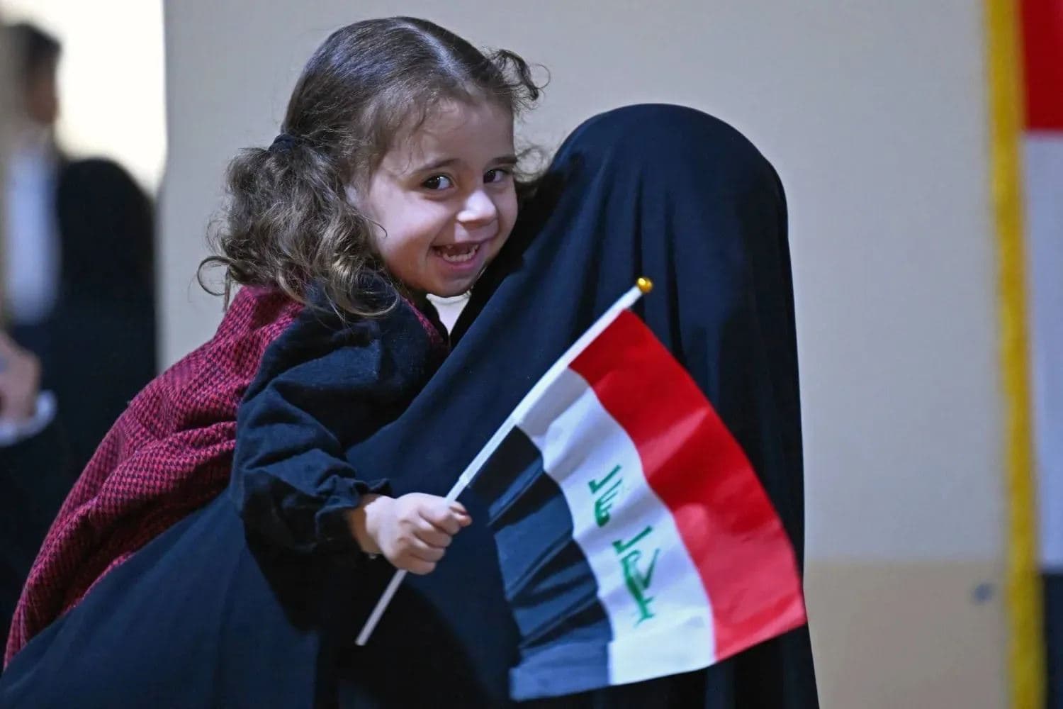 An Iraqi voter carries her child, who is holding the national flag, at a polling station in the southern city of Basra. Photo: AFP