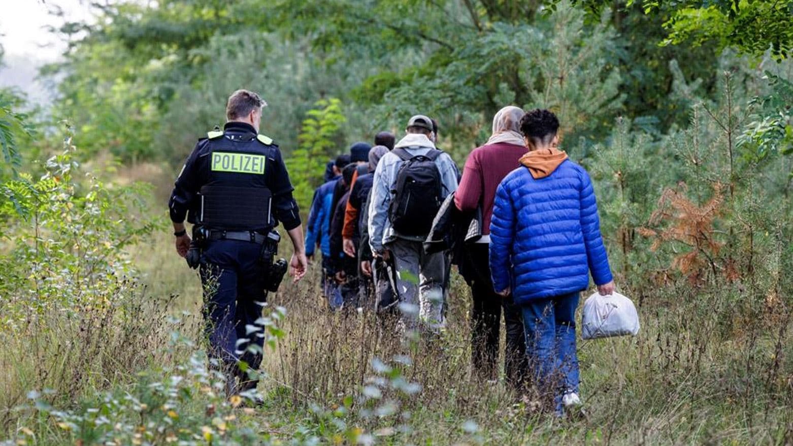   A German Federal Police officer escorts a group of migrants near Forst, eastern Germany around mid-October 2023. AFP file photo