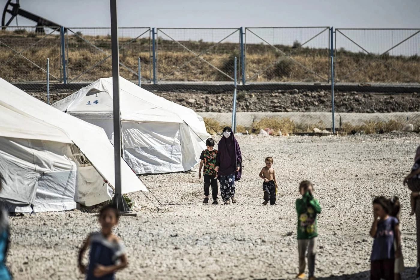 A woman walks next to a child by tents at al-Roj camp in September 2020. AFP file photo