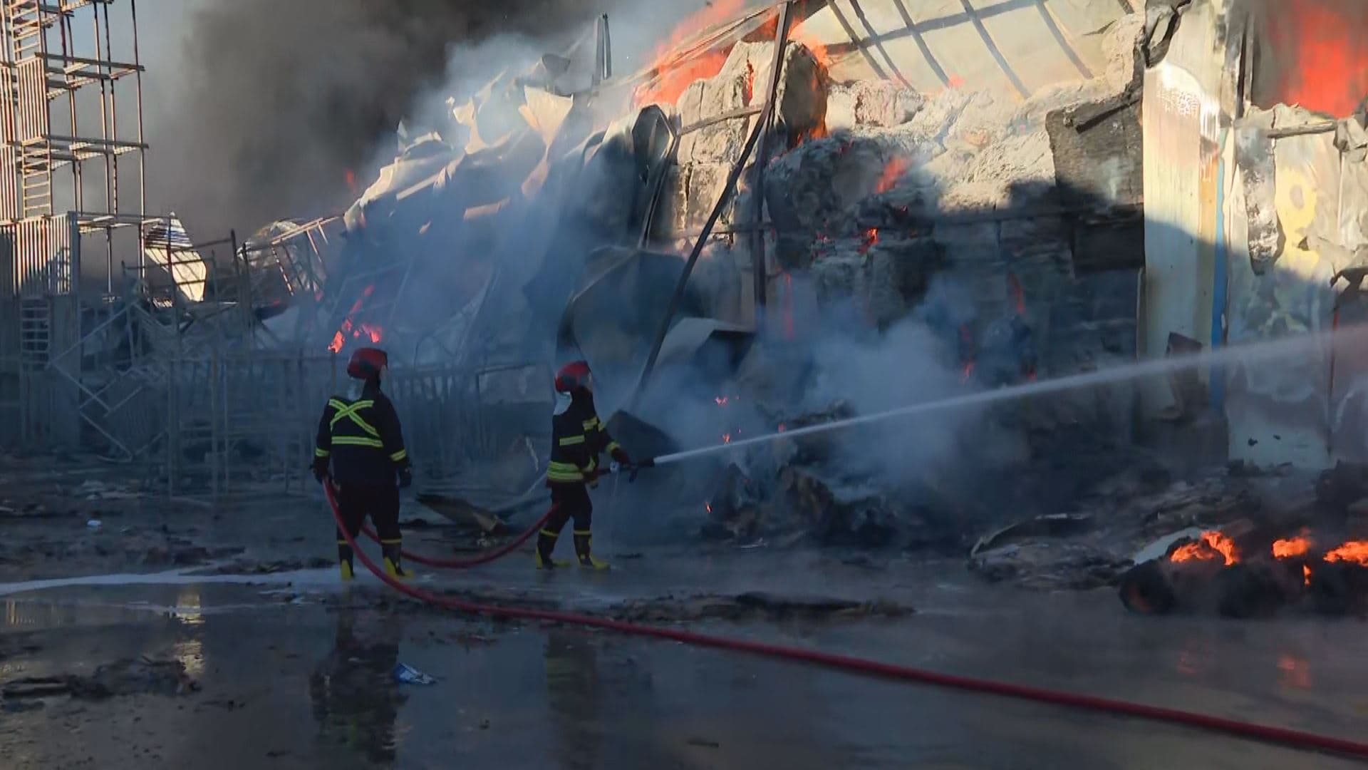 Two firefighters trying to extinguish fire at a potato chip factory in Erbil on Tuesday, January 6, 2026. Photo: Rudaw/screengrab