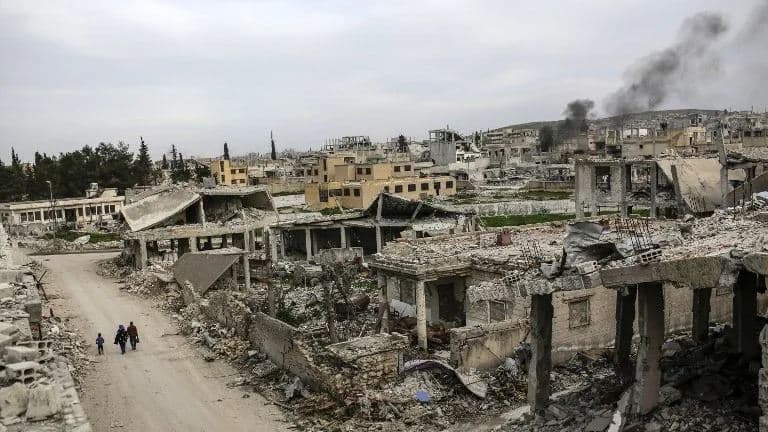 People walking along a conflict damaged street in the Syrian town of Kobane, March 27, 2015. Islamic State group fighters reentered the battleground town on June 25, 2015. Photo: AFP