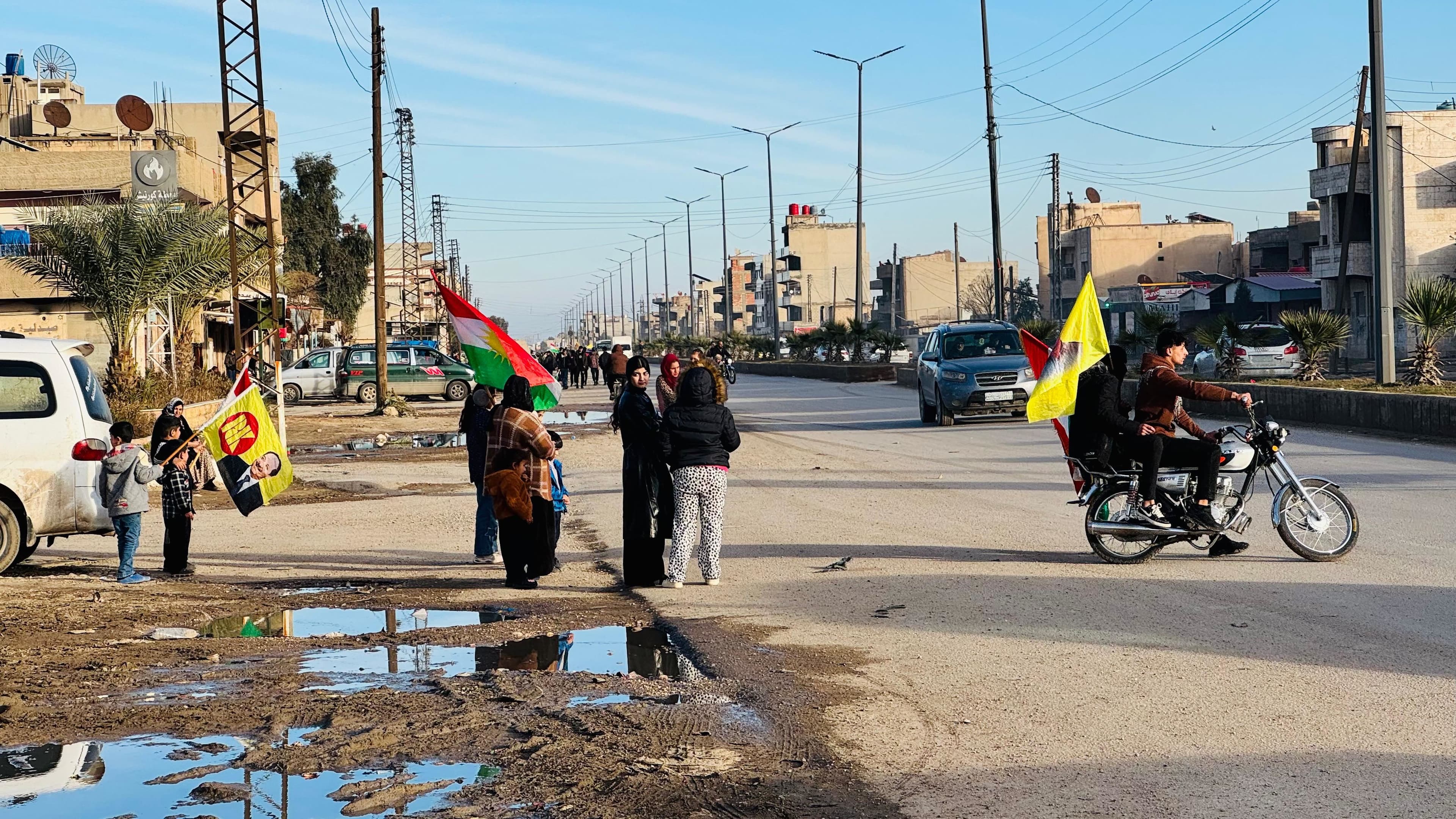 Group of children stand by the side of the road waving Kurdistan flag at the entrance to Qamishli city. Photo: Fazel Hawramy 
