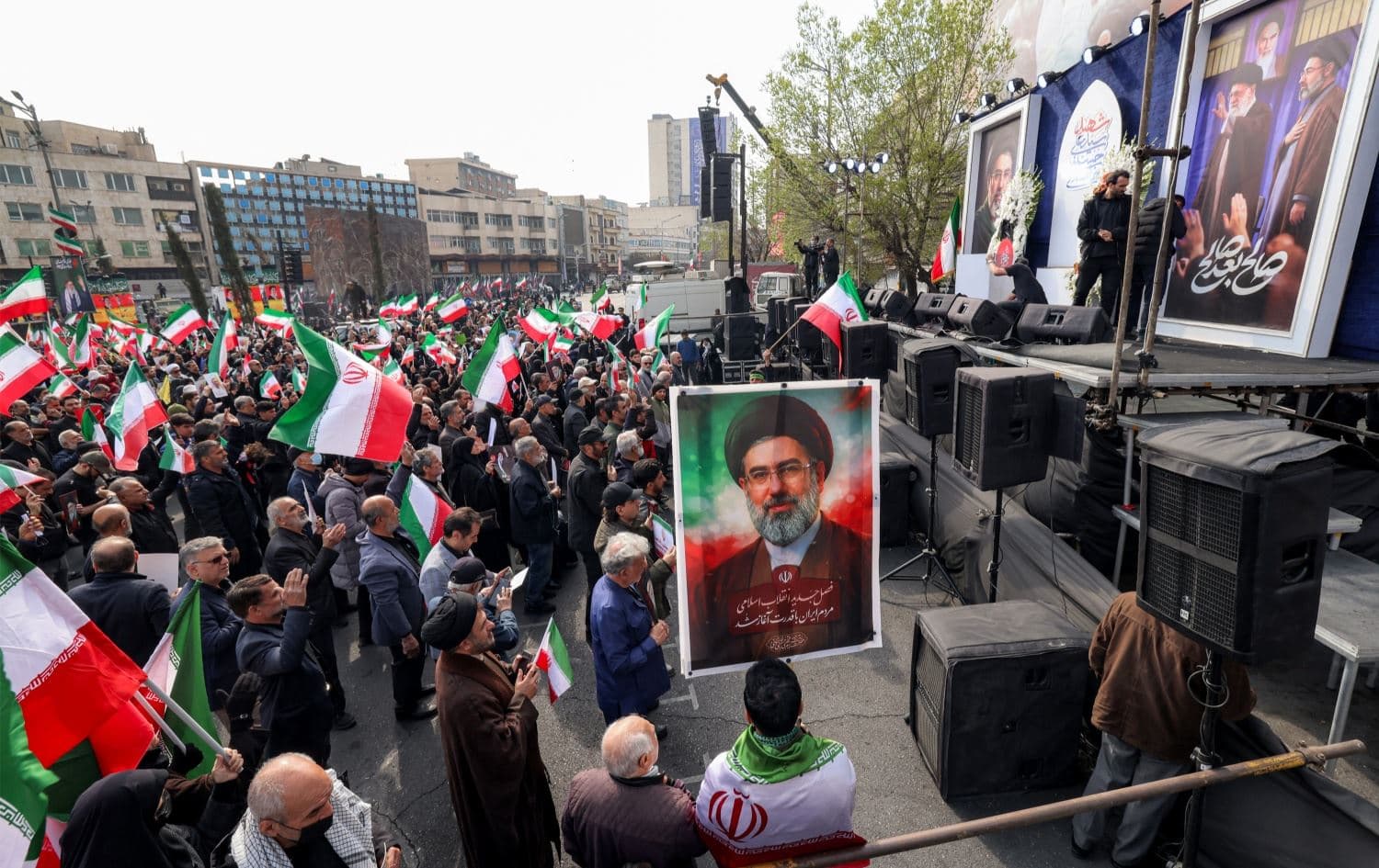 هاووڵاتییانی ئێران لە نێوەڕاستی تاران وێنەی موجتەبا خامنەیی، رێبەری نوێی کۆماری ئیسلامیی ئێرانیان هەڵگرتووە.وێنە: AFP