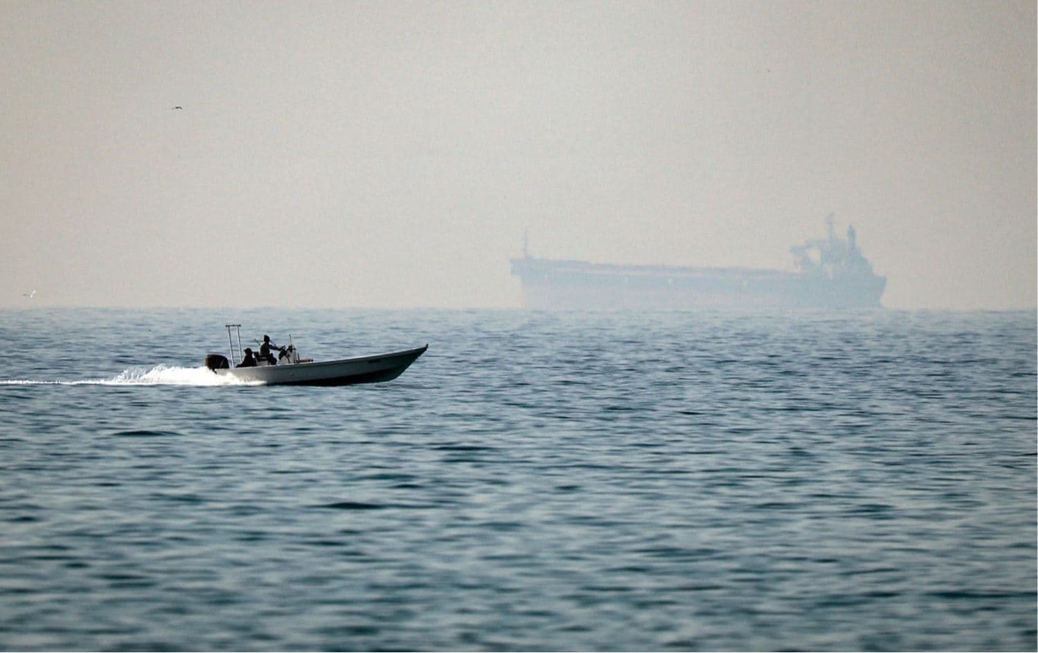 زورق يمر قرب ناقلة نفط في مضيق هرمز قبل إغلاقه- AFP