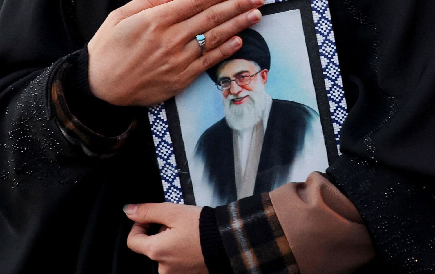 ژنێک وێنەیەکی عەلی خامنەیی، رێبەری کۆچکردووی ئێرانی بەدەستەوە گرتووە. وێنە: REUTERS