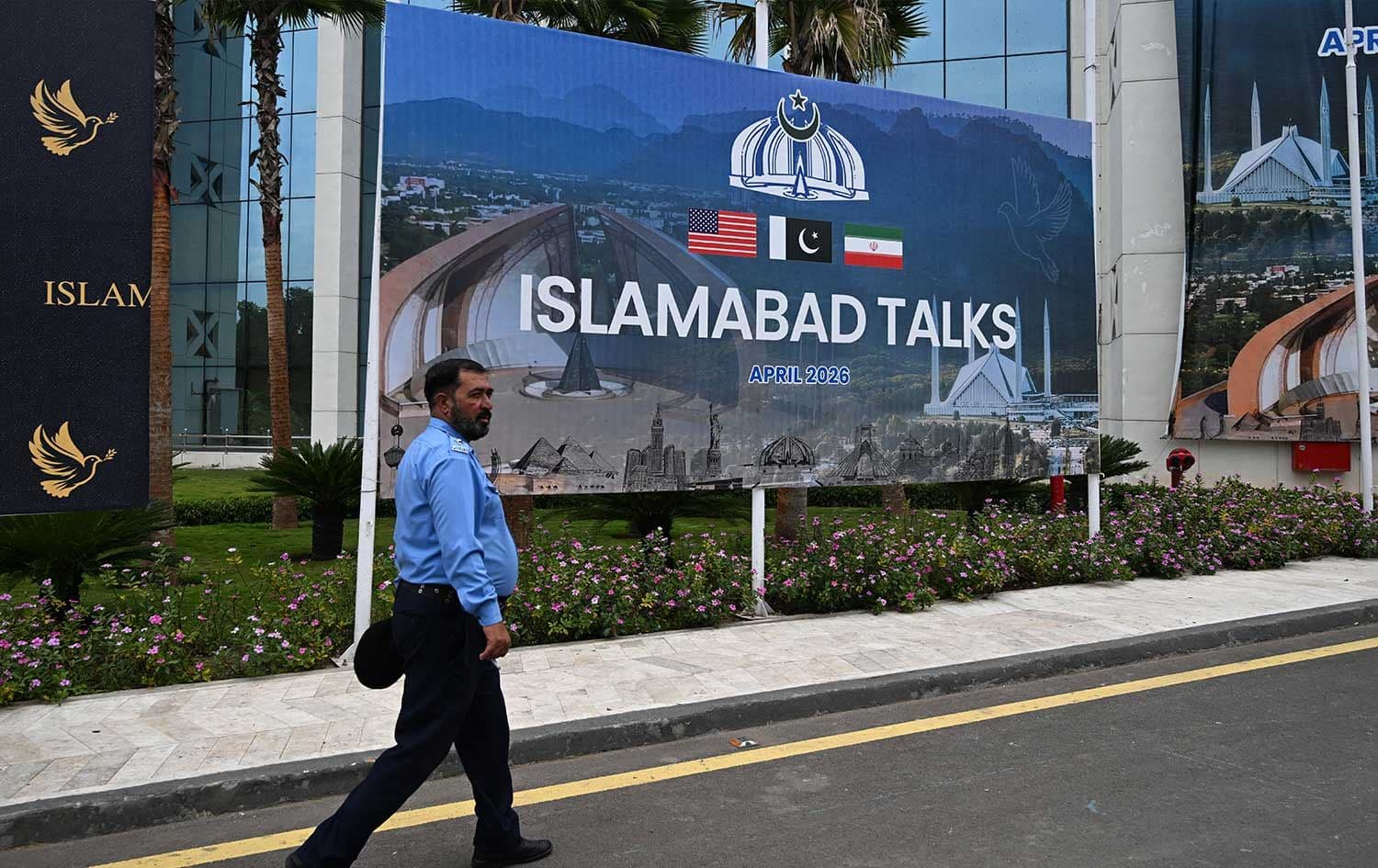 A police officer walks past a billboard for the US–Iran peace talks in Islamabad on April 11, 2026. Photo: AFP