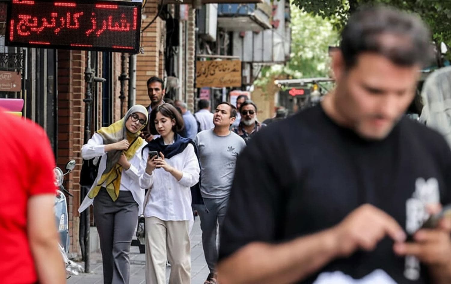 Iranians walking and browsing their phones on a street in Tehran in September 2023. Photo: AFP