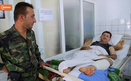 A security officer stands by one of his colleagues injured in Erbil's bomb attacks.