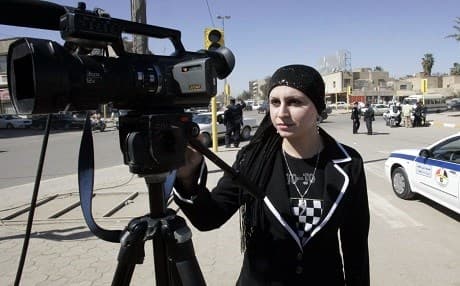 Iraqi TV reporter Hoda Haddad looks through the viewfinder of a camera as she works on a report in Baghdad. File photo: AFP