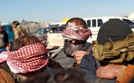 Alleged ISIS fighters, who fled from the frontline Syrian village of Baghuz, near the Iraqi border, sit blindfolded in the back of a pickup truck after being taken into custody by SDF forces. Photo: Delil Souleiman | AFP