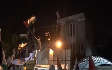 Protestors wave Palestinian and Iraqi flags outside the Bahrain embassy in Baghdad on June 28, 2019.