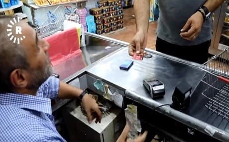 A shopowner in Baghdad, Iraq, receives payment for goods at a supermarket in the capital as officials weigh supporting more cashless initiatives. Photo: Rudaw video