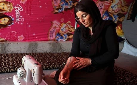 Iraq’s Yezidi survivor Layleh Shemmo looks at her tattoo bearing the names of her two sons at a tent in the Khonke camp for displaced persons in northwestern Iraq, June 24, 2019. Photo: Safin Hamed / AFP