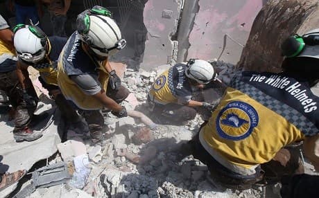 Members of the Syrian Civil Defence known as "White Helmets" try to pull a man from the rubble of a building following an airstrike by Syrian regime forces in Maar Shurin on the outskirts of Maaret al-Numan in northwest Syria on July 16, 2019. Photo: Abdulaziz Ketaz | AFP