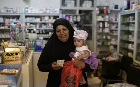 A Syrian woman leaves a pharmacy after buying medicine in the Syrian capital, Damascus on Wednesday 24 July. Photo: AP/ Hassan Ammar