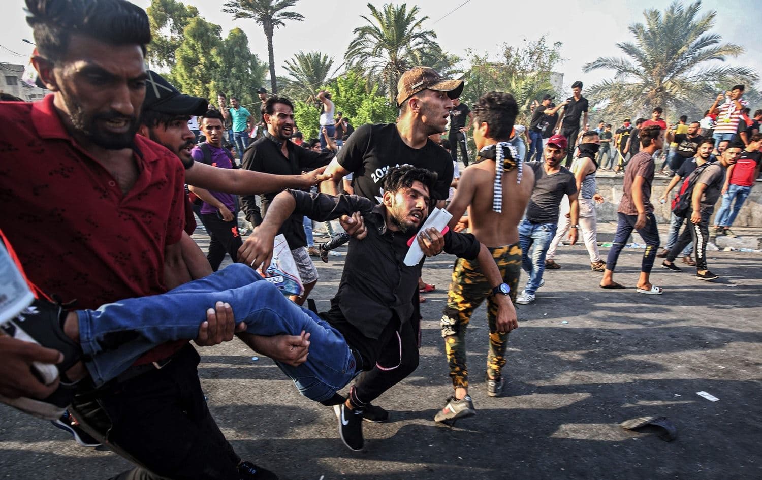Men carry away a protester injured during clashes with riot police during a demonstration against state corruption and poor services, between the Iraqi capital Baghdad's Tahrir Square and the high-security Green Zone district, October 1, 2019. Photo: Ahmad al-Rubaye / AFP