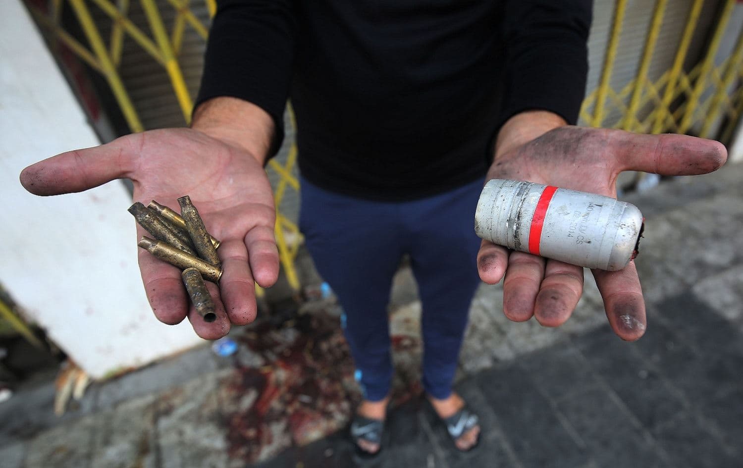 A protester holds in his hands the casings of live rounds (L) and a spent tear gas canister (R) reportedly fired by riot police during clashes in the Iraqi capital Baghdad, October 3, 2019. Photo: Ahmad al-Rubaye / AFP