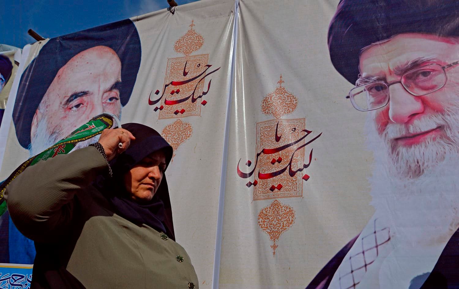 A Shiite Muslim pilgrim walks in front of posters of Iran's Supreme Leader Ayatollah Ali Khamenei (R) and the spiritual leader of the Shiite community Grand Ayatollah Ali Sistani, during a procession from the holy Iraqi city of Najaf to the central shrine city of Karbala, Iraq on October 12, 2019, ahead of the Arbaeen religious festival. Photo: Haidar Hamdani/AFP