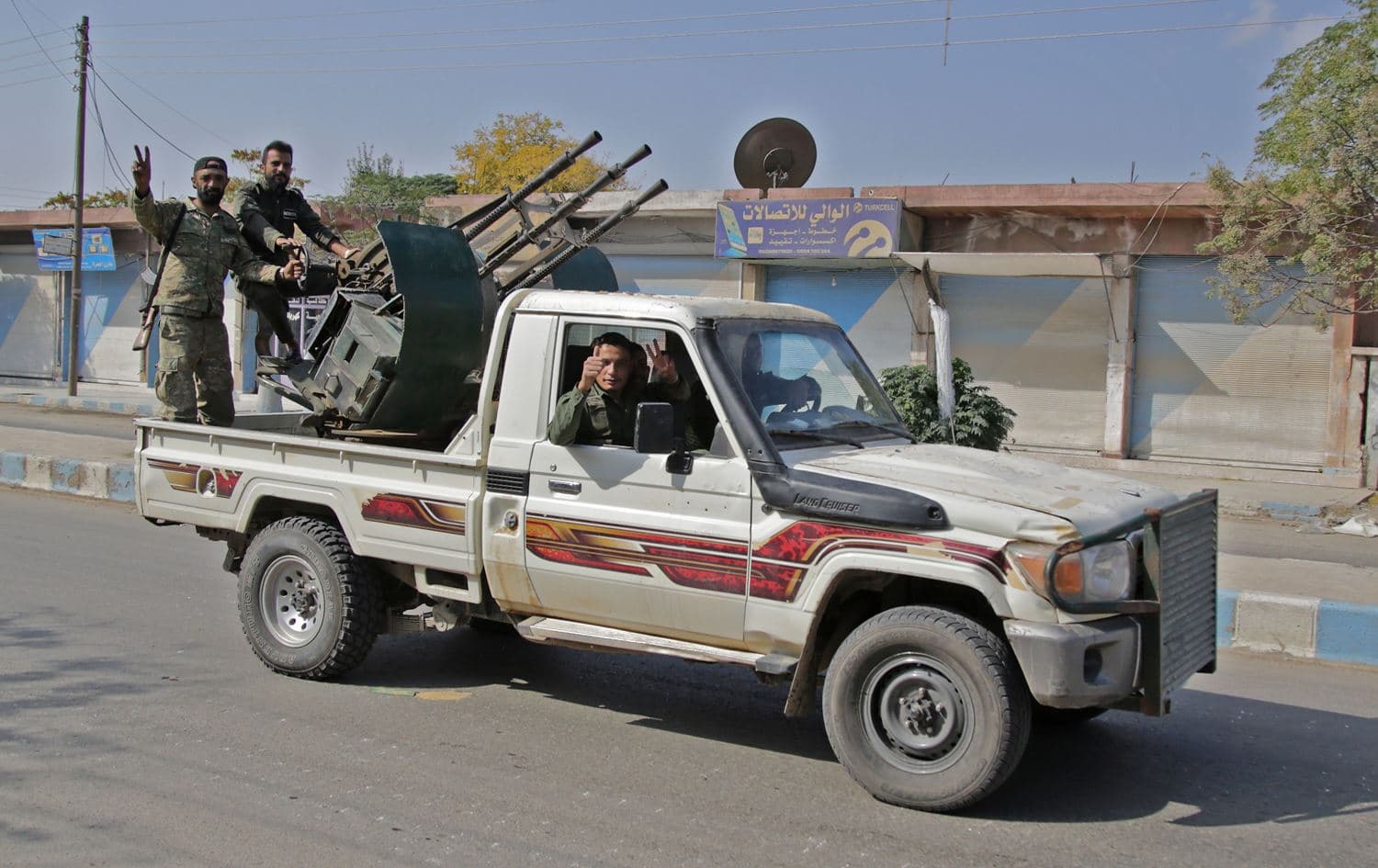 Turkish-backed Syrian fighters ride in the back of a pick up truck in the Syrian border town of Tal Abyad on October 18, 2019, a day after a ceasefire was announced. Photo: Bakr Alkasem/AFP