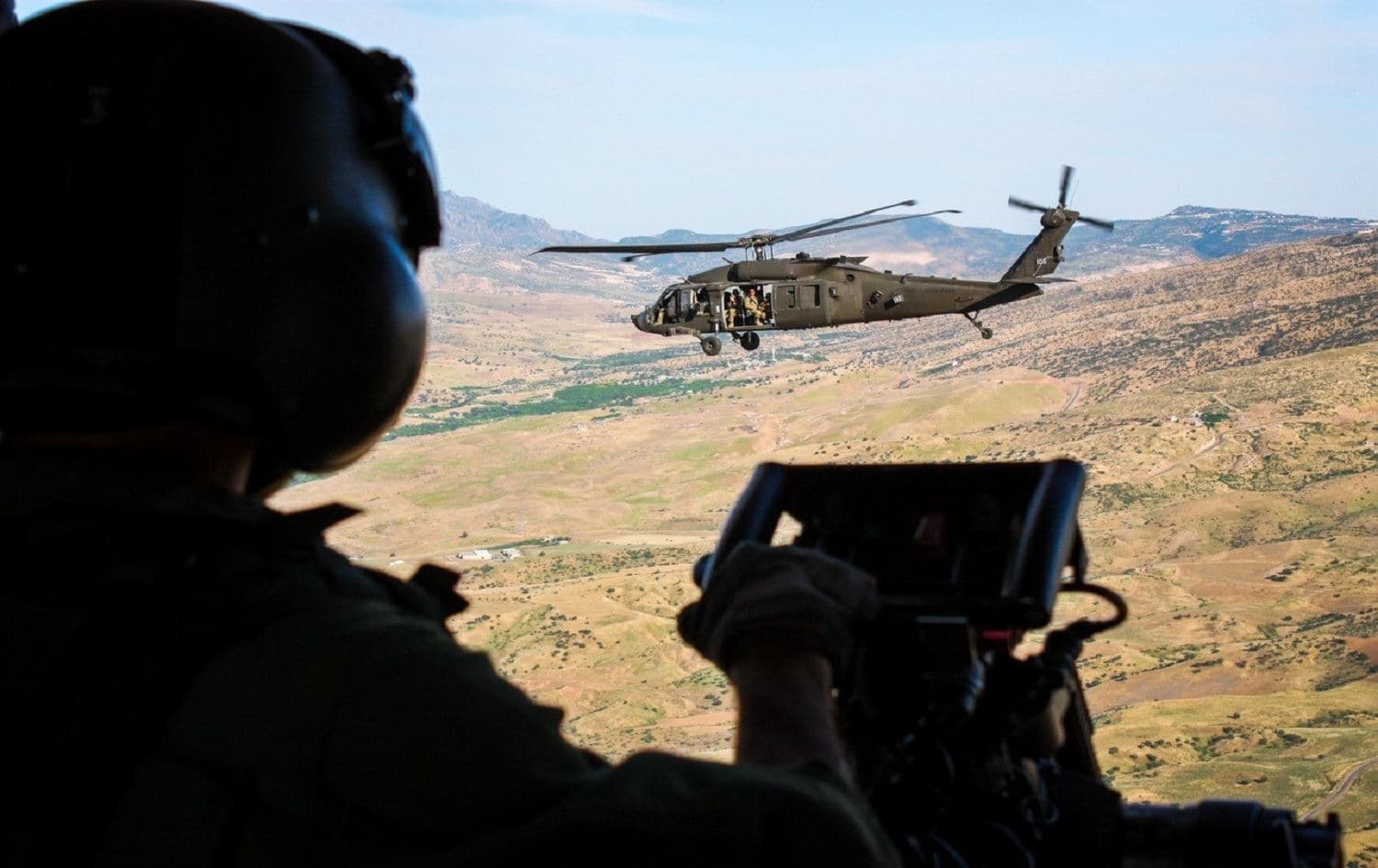 An Italian Army crewmember looks out an NH-90 helicopter as it flies alongside an American UH-60 helicopter during a multinational flight movement near Erbil, Iraq on May 31, 2019. Photo: Operation Inherent Resolve / Task Force Griffon