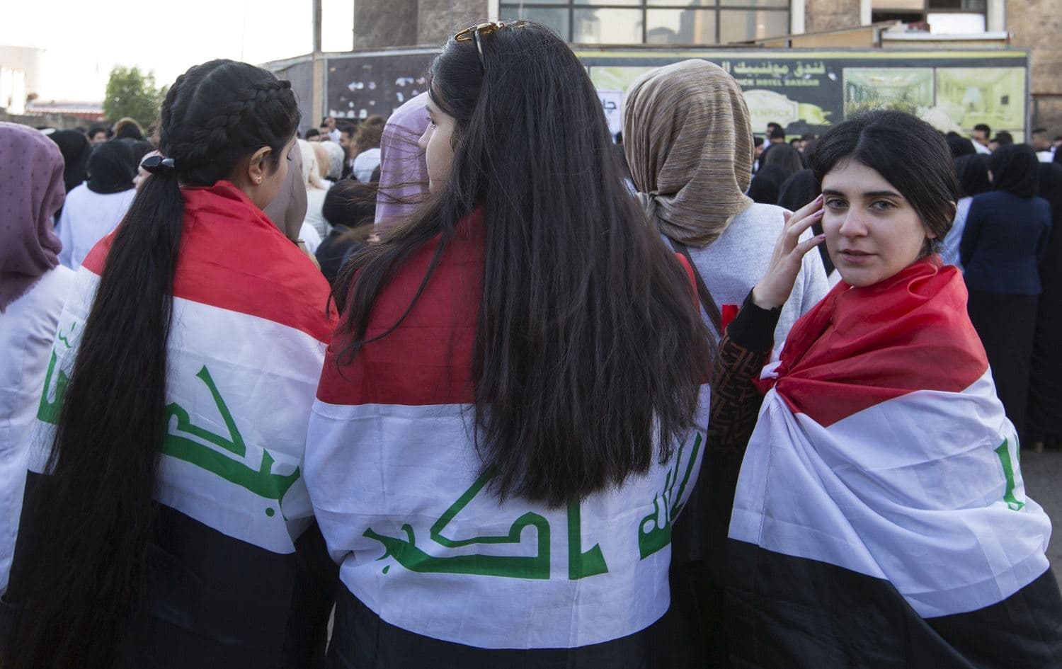 Iraqi university students, draped in national flags, rally to show support for local products and to encourage the boycott of imported Iranian goods in the southern city of Basra on December 8, 2019. Photo: Hussein Faleh / AFP