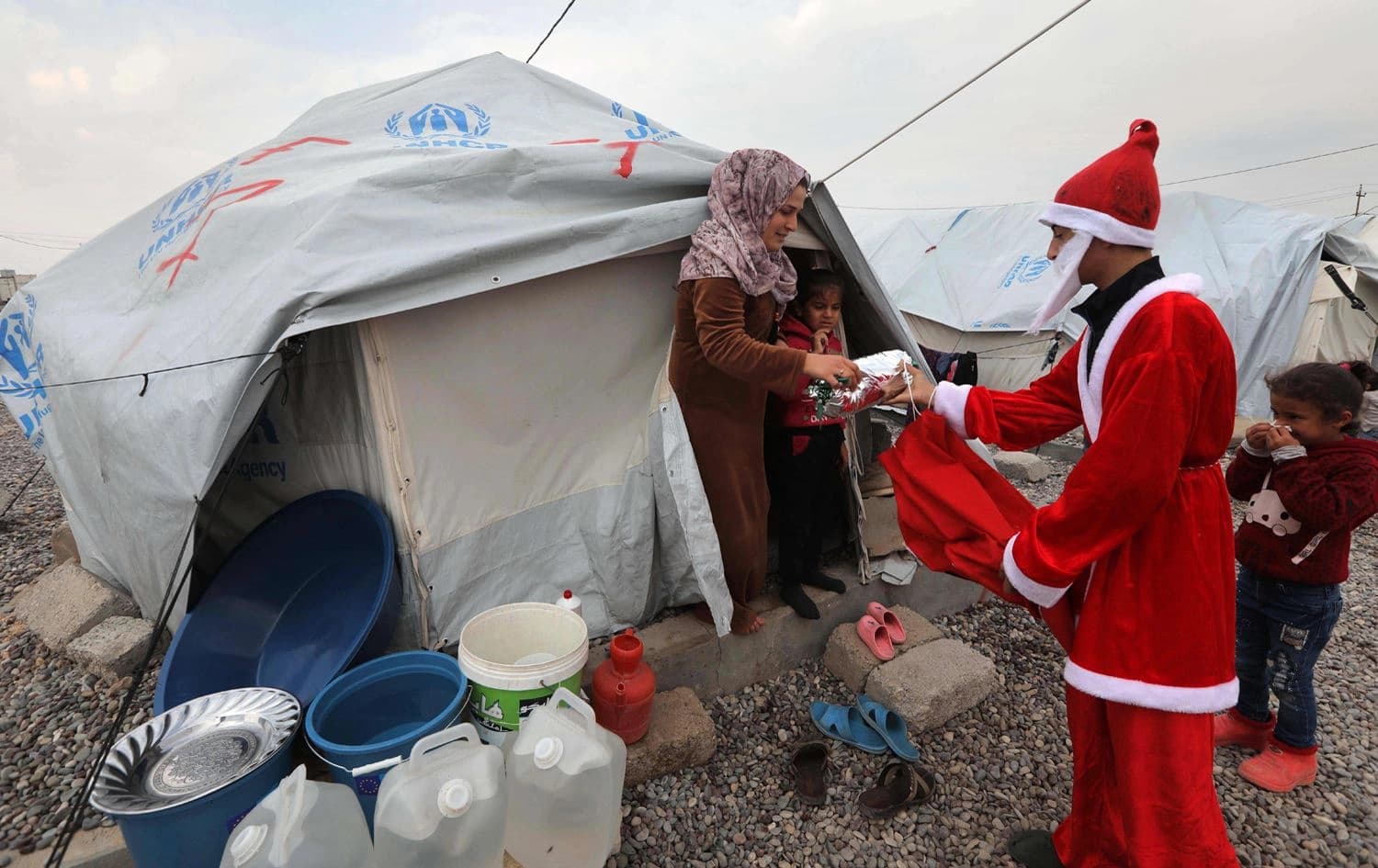 A Syrian man dressed as Santa Claus gives gifts to children at Gawelan refugee Camp, 40 kms west of Arbil, the capital of Kurdistan Region, on December 26, 2019. Photo: Safin Hamed / AFP