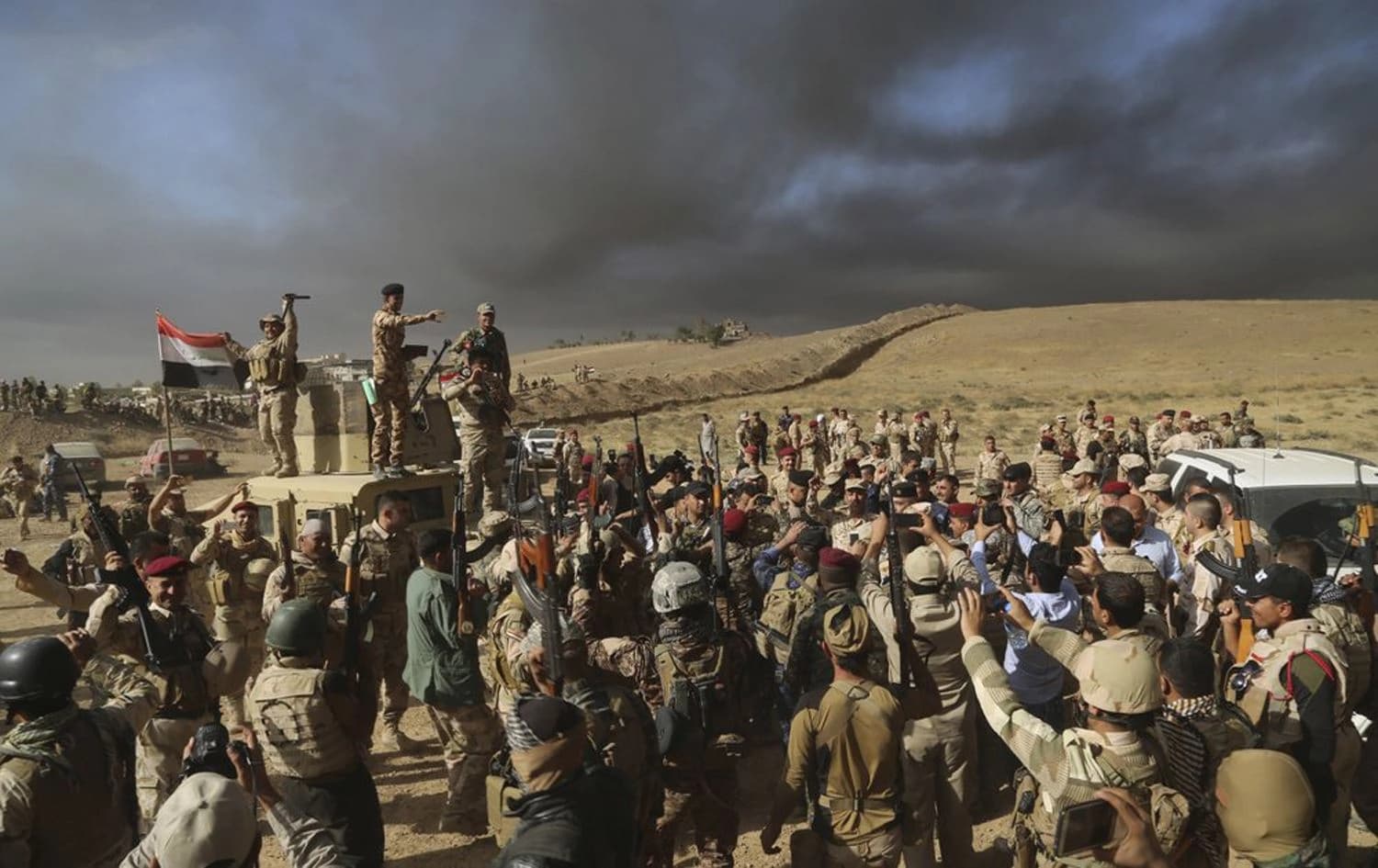 Iraqi army soldiers raise their weapons in celebration on the outskirts of Mosul, Iraq, Thursday, Oct. 20, 2016. Photo: AP