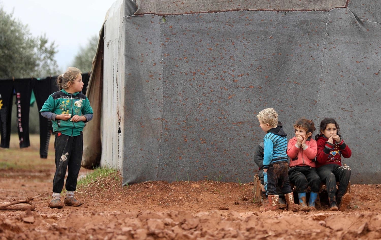 Syrian children, who fled air strikes in their hometown, are pictured near tents at an informal camp for displaced people where they live with their families in northern Syria's Idlib province on January 7, 2020. Photo: Omar Haj Kadour/AFP