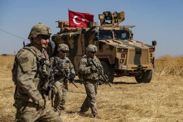 US troops walk past a Turkish military vehicle during a joint patrol with Turkish troops on the outskirts of Tal Abyad, northern Syria on September 8, 2019. File photo: Delil Souleiman / AFP