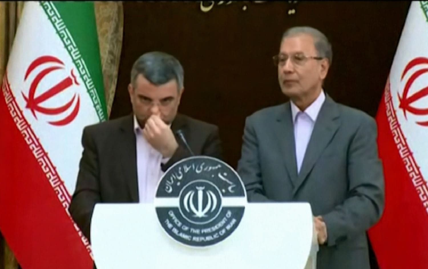 Iraj Harirchi (left), head of an Iranian government task force on the coronavirus, could be seen coughing and heavily sweating at a televised news conference in Tehran on February 24, 2020. Screenshot via Iran Press / AFP