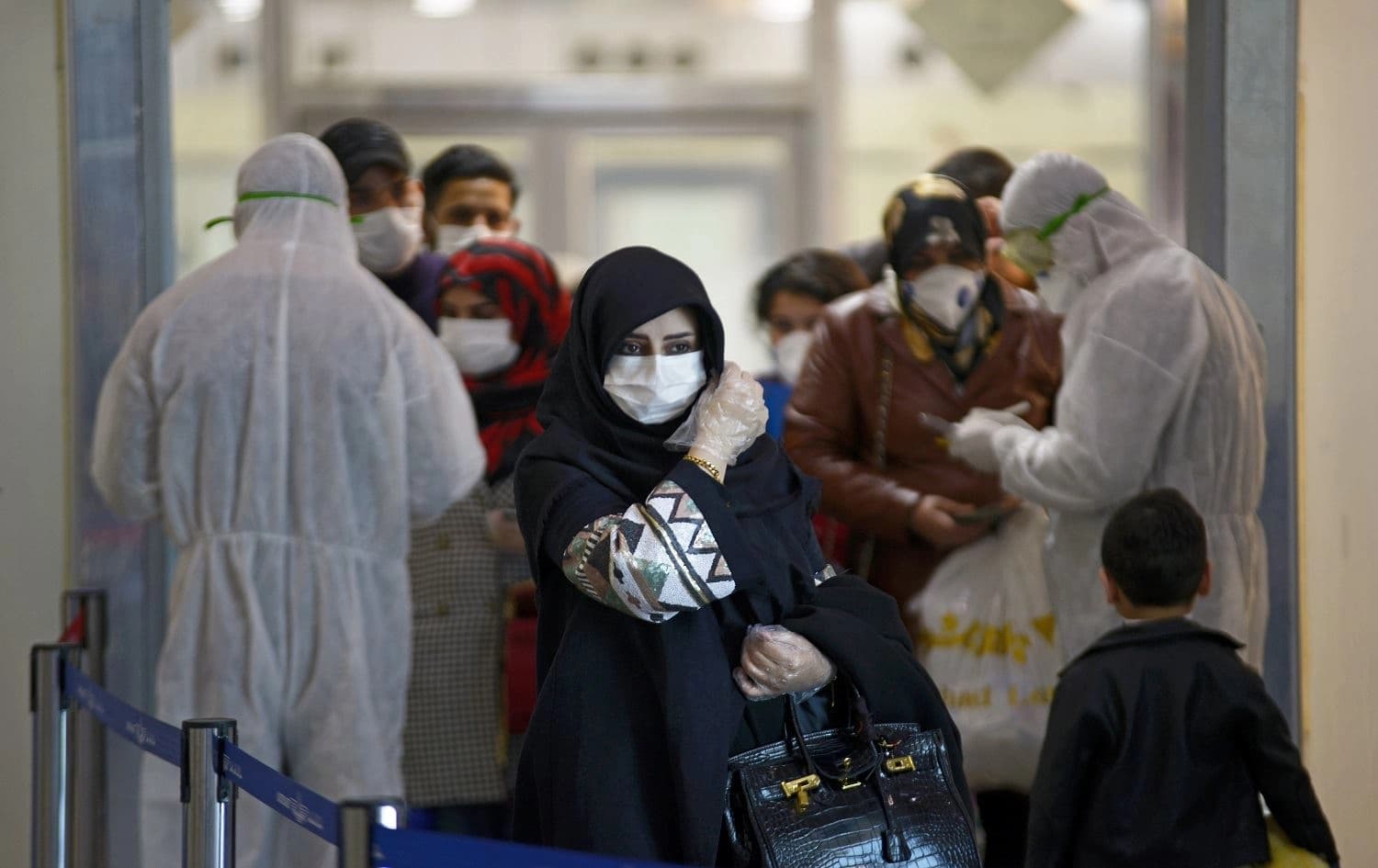 Medical staff in protective gear distribute information sheets to Iraqi passengers returning from Iran at Najaf International Airport on March 5, 2020. Photo: Haidar Hamdani/AFP.