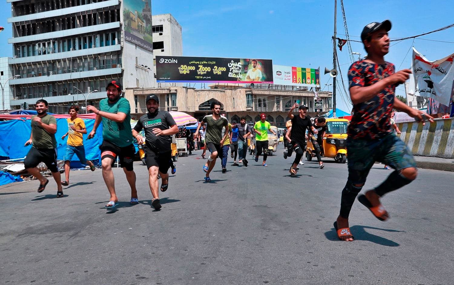 Anti-government protesters run for cover during skirmishes near Baghdad’s Tahrir Square Tuesday, April 21, 2020. Photo: Hadi Mizban/ AP