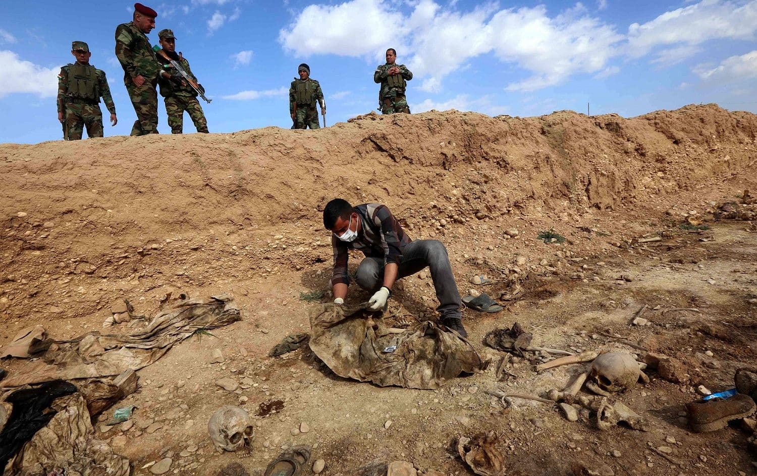 An Iraqi man inspects the remains of members of the Yezidi minority killed by the Islamic State (ISIS) group at a mass grave in Shingal, February 3, 2015. File photo: Safin Hamed / AFP