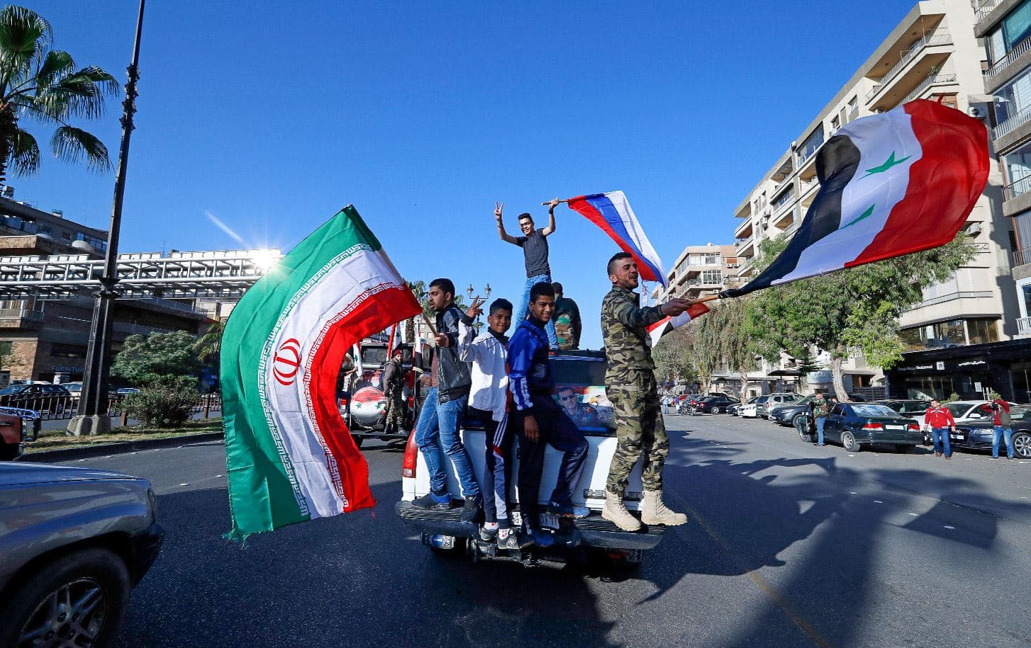Syrian government supporters wave Syrian, Iranian and Russian flags as they chant slogans against US President Donald Trump. File photo: Hassan Ammar / AP