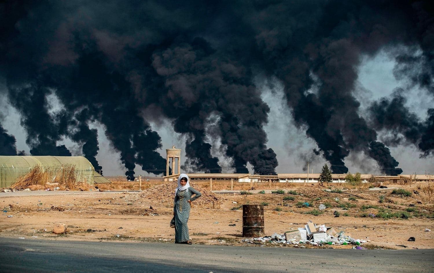 A woman stands along the side of a road on the outskirts of Tel Tamr on October 16, 2019. Photo: Delil Souleiman/AFP