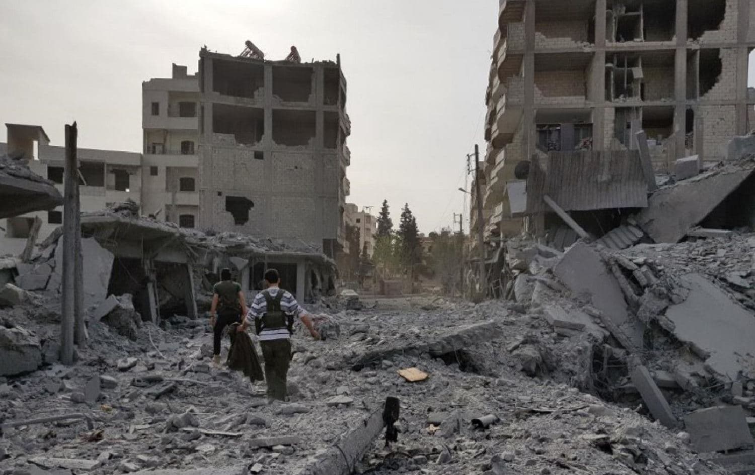 Young men walk amid the destruction in Afrin in March 2018, after Turkish-led forces entered the city. File photo: AFP