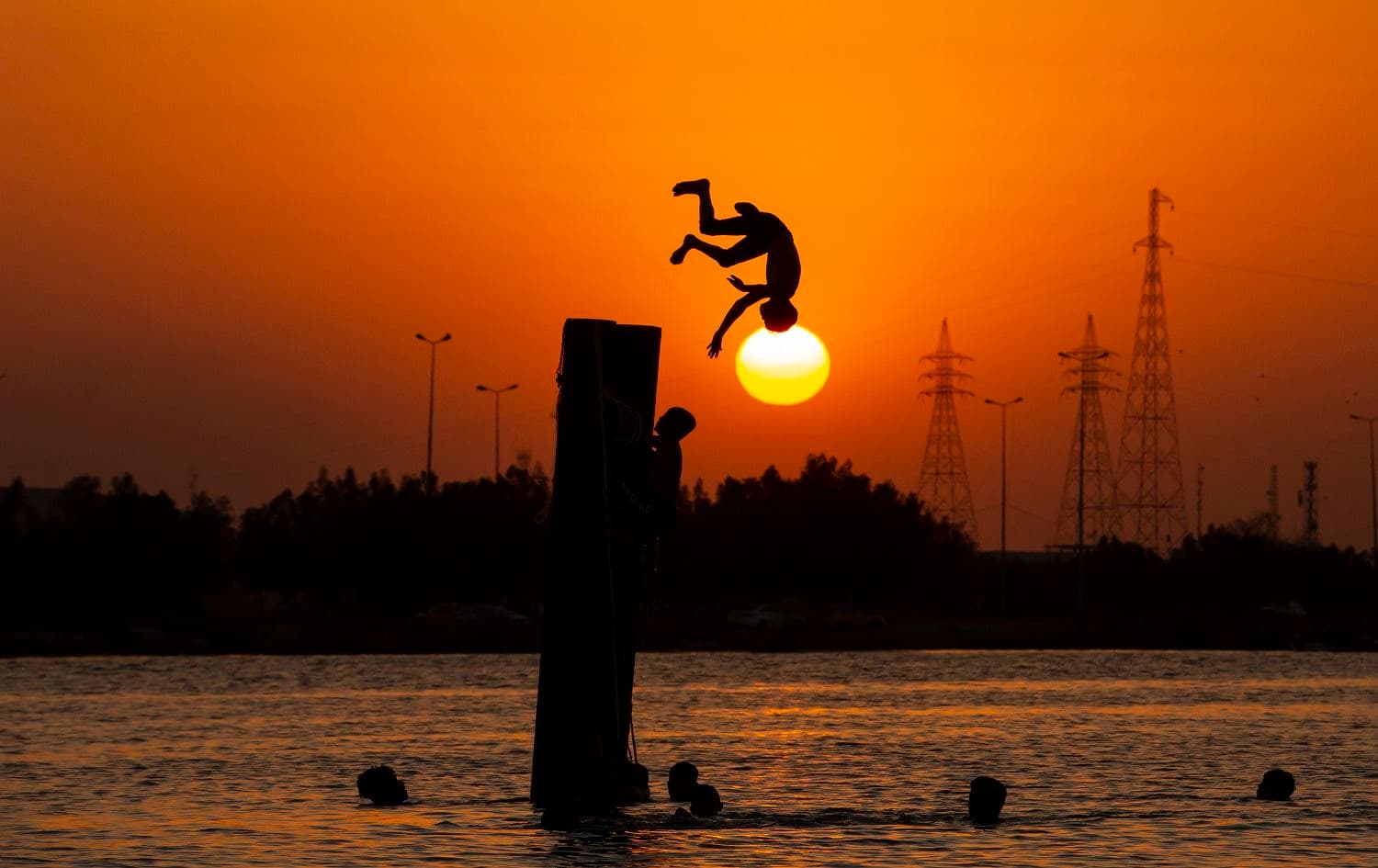 An Iraqi youth dives into the river in the Shatt Al-Arab river in the southern port city of Basra on August 6, 2020. Photo: Hussein Faleh / AFP