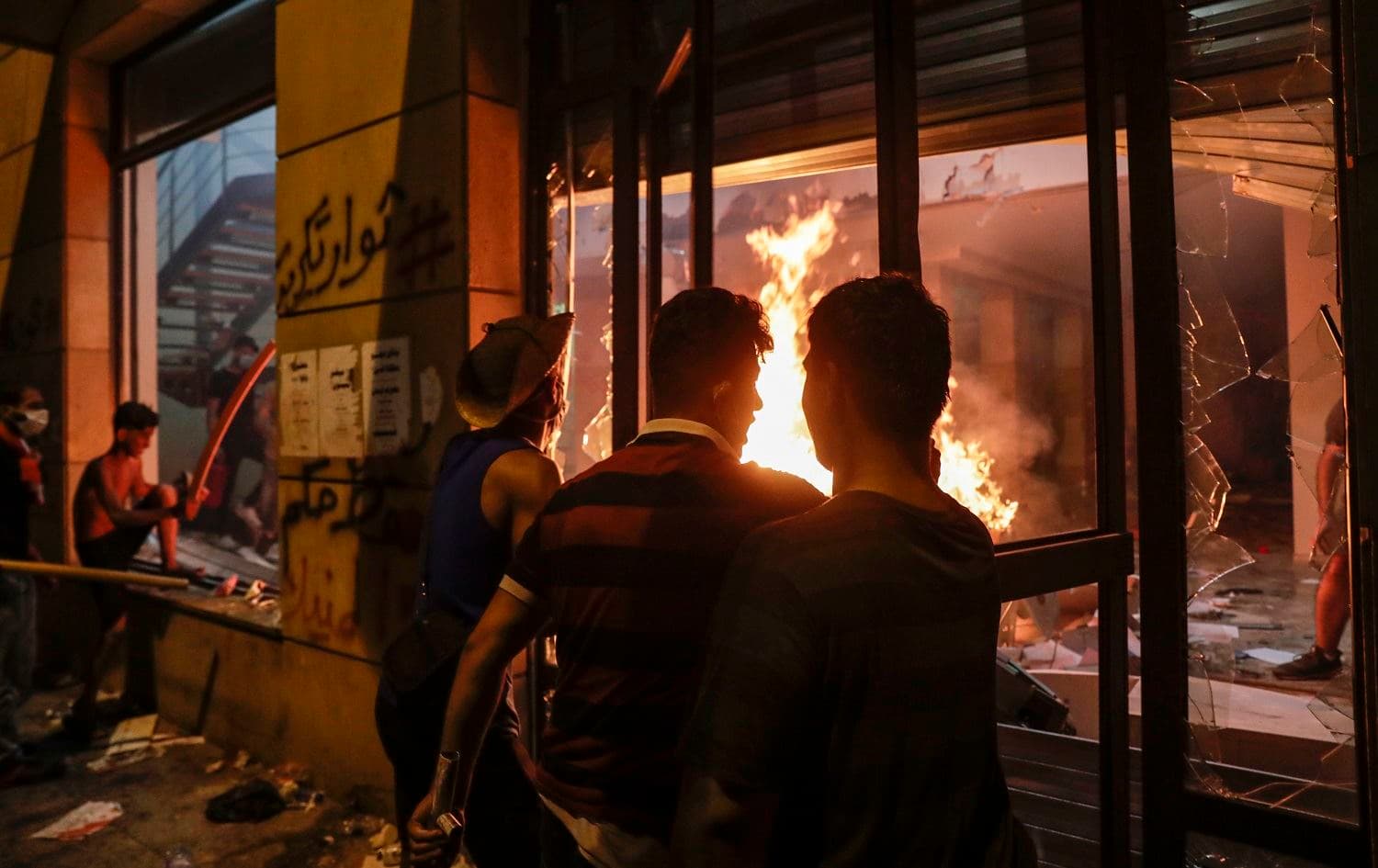 Lebanese protesters watch the flames inside the headquarters of the Association of Banks in Lebanon in downtown Beirut on August 8, 2020. Photo: Anwar Amro / AFP