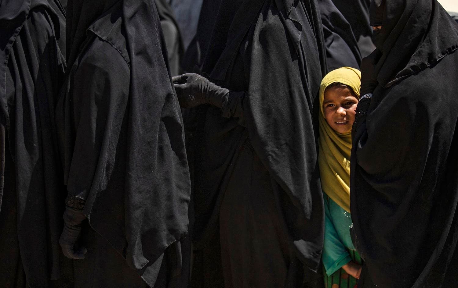 A girl stands in line to receive aid with women at al-Hol, northeastern Syria, on August 18, 2020. Photo: Delil Souleiman / AFP